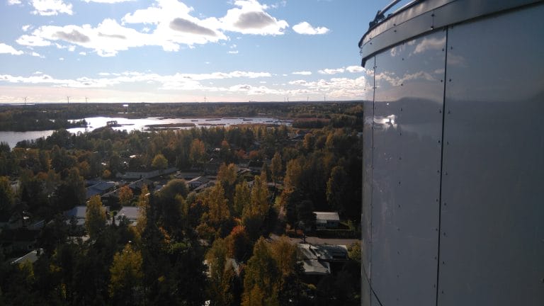 Näkymä vesitornin sivulta merelle päin puiden latvojen yläpuolelta. Taustalla siintää meri ja sinivalkoinen taivas.