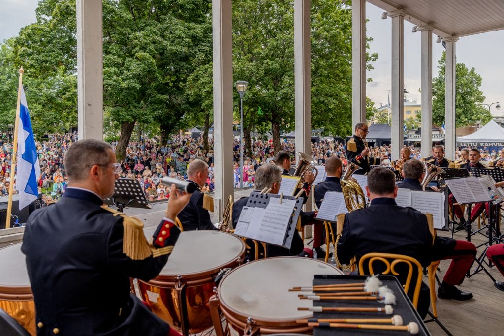 Soittokunta lavalla ihmisjoukko takanaan.