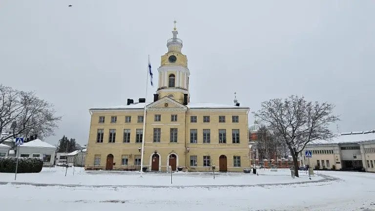 Raatihuone, jonka talvisella pihalla lippu salossa.