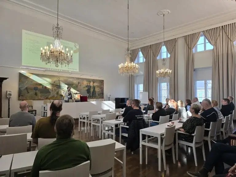 Ihmiset istumassa salissa.