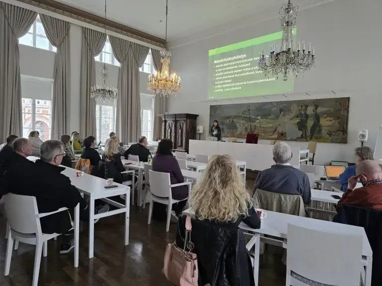 Ihmisiä salissa istumassa.