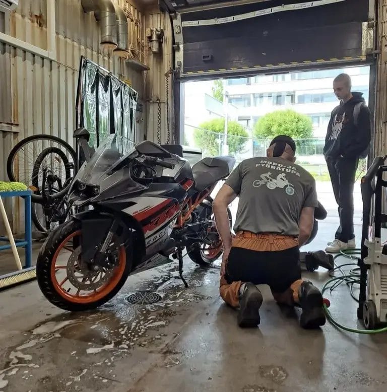 Mopoa huoltamssa kaksi ihmistä tallissa.