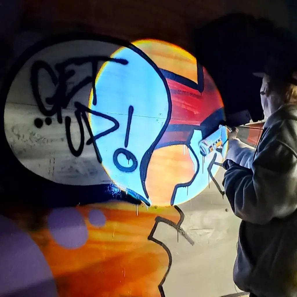 Graffititaiteilija BOGAR maalaa seinään graffitia spraymaalilla.
