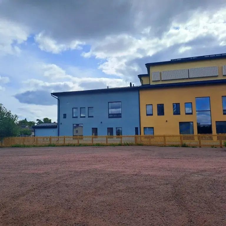 Entisen keskuskoulun tontti jossa hiekkakenttä ja taka-alalla päiväkotirakennus.