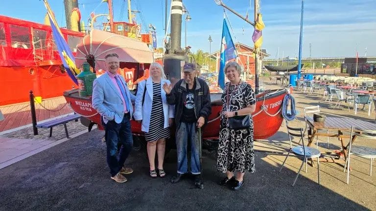 Kaupungin virkamiehet Patun kanssa pienen veneen edustalla.