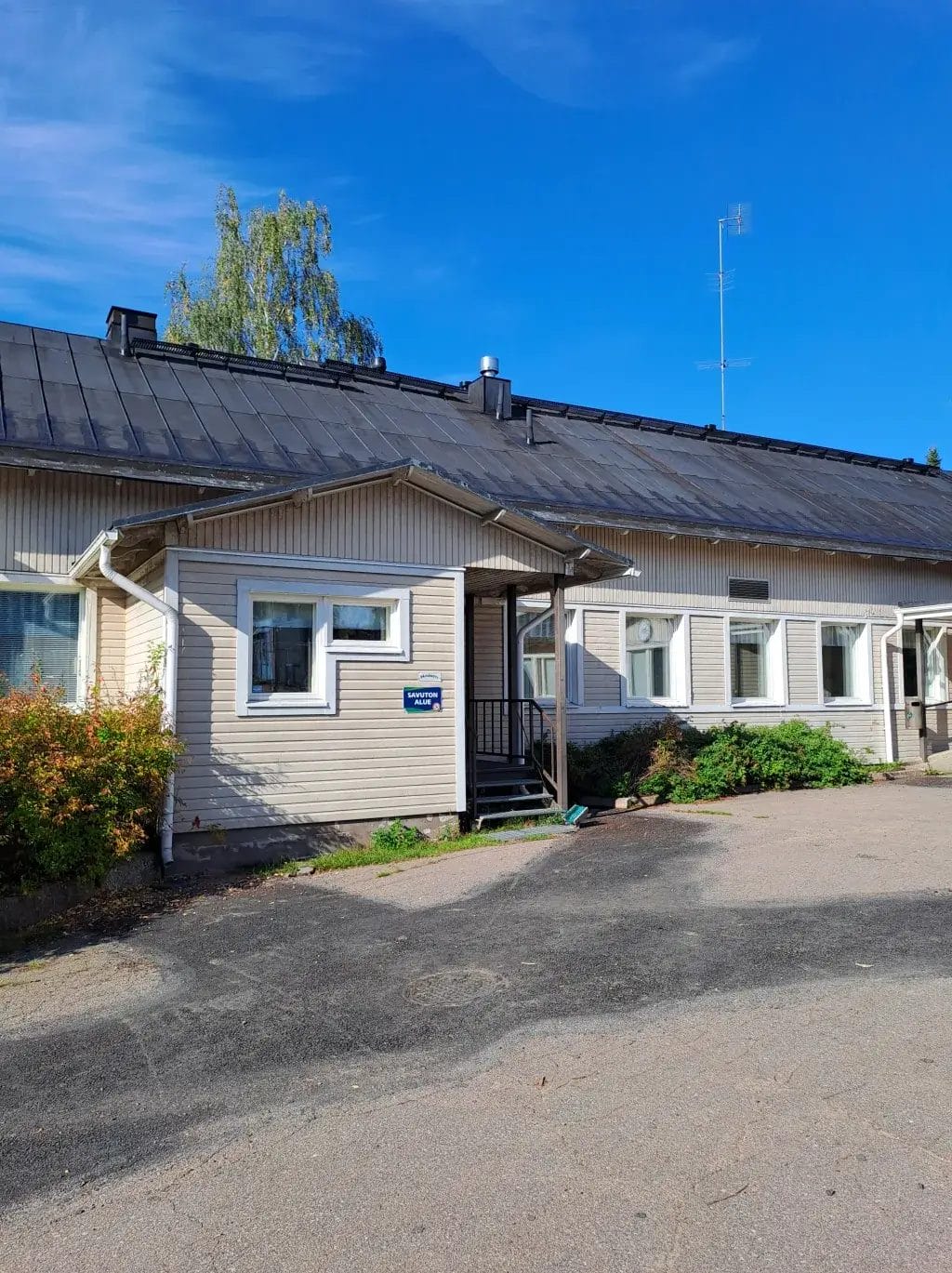 Kuvassa Pyhällön päiväkodin julkisivu ja sisääntulokuisti, vaalea puurakennus ja hiekkapihaa