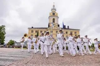 Soittokunta valkoisissa uniformuissa Raatihuoneen edessä.