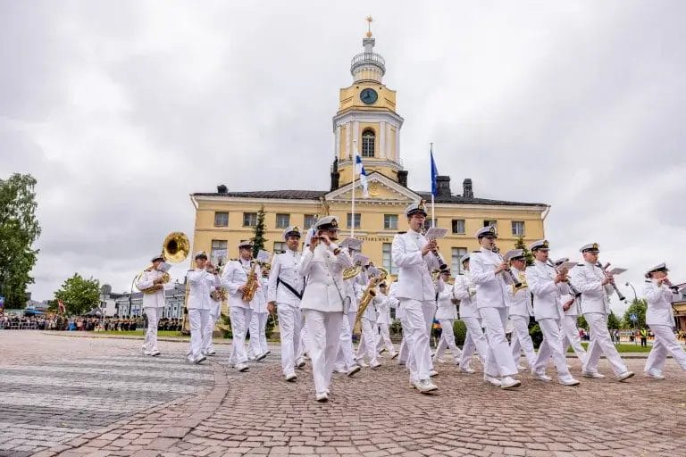 Soittokunta valkoisissa uniformuissa Raatihuoneen edessä.