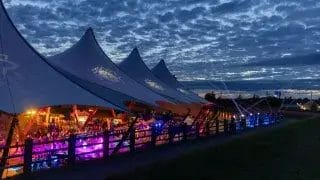 Hamina Bastionin telttakatos ja telttakatoksen alla tapahtumavieraita iltavalaistuksessa.