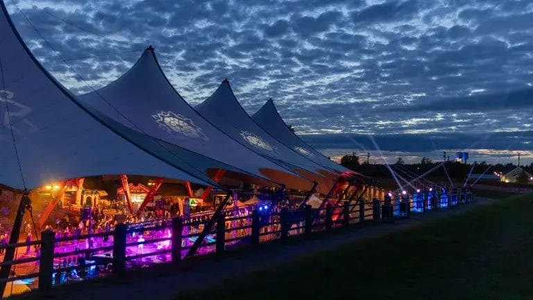 Hamina Bastionin telttakatos ja telttakatoksen alla tapahtumavieraita iltavalaistuksessa.