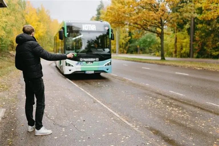 ihminen odottamassa bussipysäkillä ja bussi tulossa.