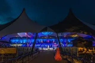 Bastionin telttakatos ja marssishow iltavalaituksessa teltan sisällä. Nainen punaisessa mekossa kävelee teltan alle ramppia pitkin.