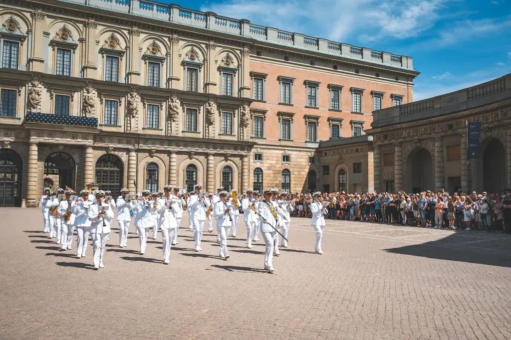 Valkoisiin uniformuihin pujeutunut soittokunta ison linnan edessä.