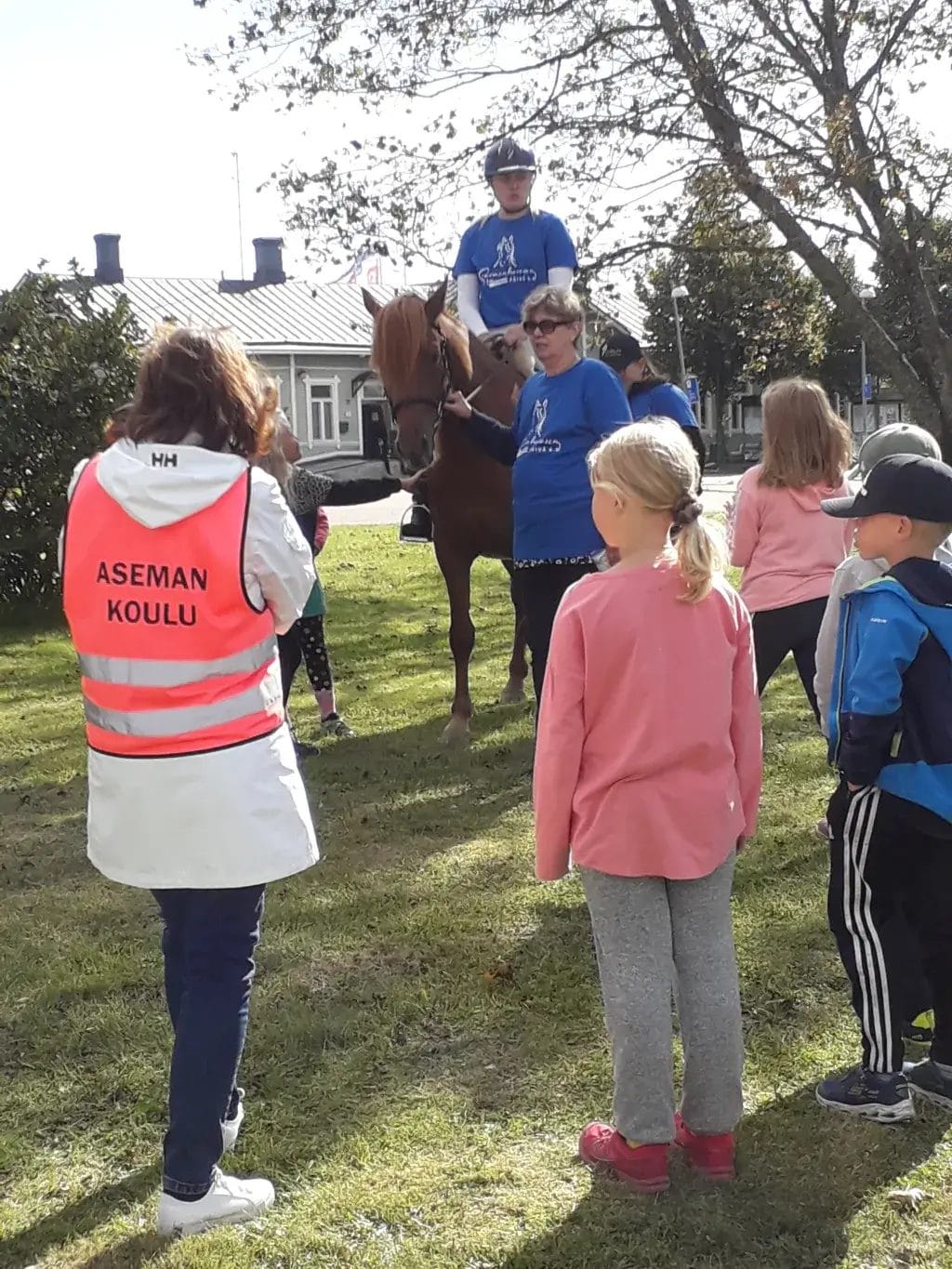Ratsukko ja lapsia sekä aikuisia katsomassa heitä.