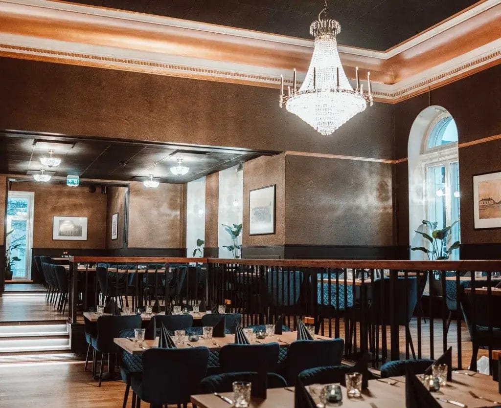 Eavintolasali, jossa katossa kristoillikruuni ja salissa katettuja pöytäryhmiä.