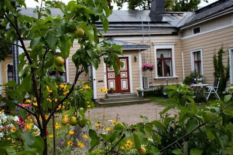 Vanha puutalo vahreän kasvuston takana.