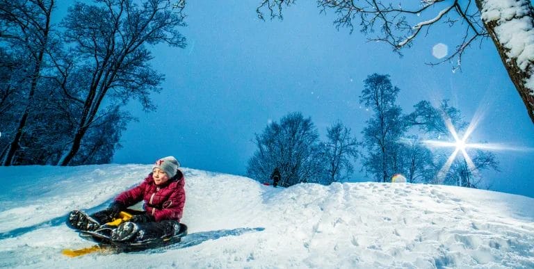 Lapsi laskemalla pulkalla lumista rinnettä.