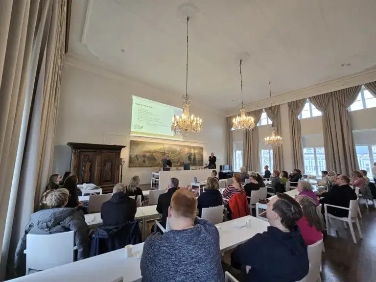 Ihmisiä Haminan valtuustosalissa istumassa,