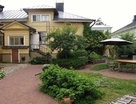 Keltainen puutalo, jonka edessä vehreä piha.