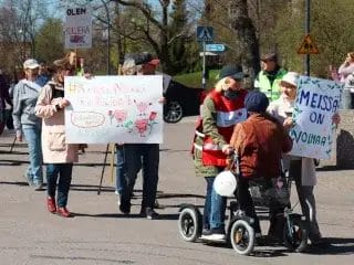 Kulkueen osallistujia, joista osa kulkee kävellen ja osa rollaattorin kanssa.